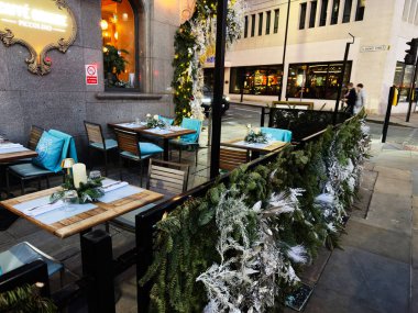 Manchester, İngiltere - 10 Aralık 2025: Manchester 'da Cafe Grande Piccolino Cafe açık hava oturma, şenlik yeşilliği ve sıcak mum ışığı ile.