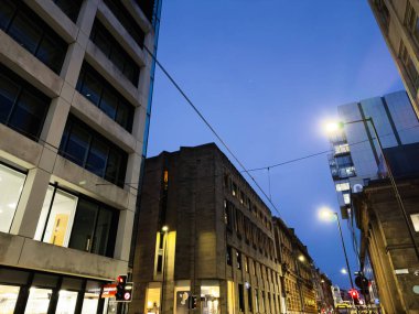 Manchester, İngiltere - 10 Aralık 2025: Manchester 'da alacakaranlık, Charlotte caddesi cam ve taş mimari ile kaplı, sokak lambalarıyla aydınlatılmış canlı bir şehir.