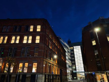 Manchester, UK - December 10, 2025: Night scene in Portland St, Manchester, UK with brick buildings, warm window lights, and a bright glass atrium.