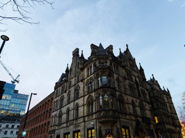 Manchester şehir merkezindeki tarihi Gotik bina berrak mavi gökyüzünün altındaki modern cam yapının yanında..