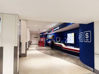 Manchester, İngiltere - 13 Aralık 2025: Mavi duvarları, kırmızı beyaz tezgahı ve müşterileri olan modern bir terminalde döviz masası.