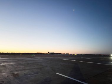 Manchester, İngiltere - 13 Aralık 2025 Manchester Havaalanı 'nda sakin bir şafak, soluk hilal altında uçak.