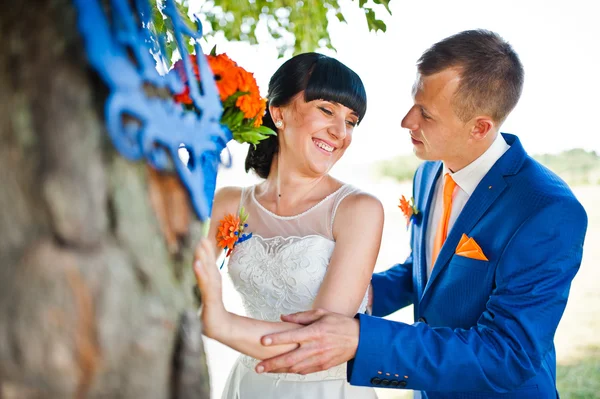 Улыбающаяся свадебная пара рядом с деревом — стоковое фото