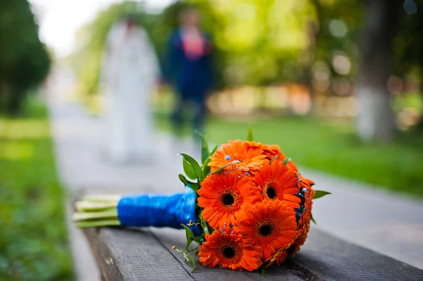 Orangefarbener Hochzeitsstrauß Gerbera mit Ringen an der Holzbank — Stockfoto