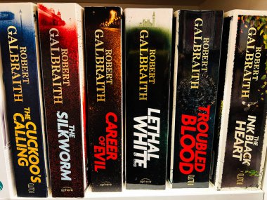 Londra, İngiltere - 12 Aralık 2025: Kitaplıkta altı Robert Galbraith romanı, kalın dikenler ve gizemli titreşimler.