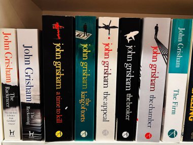 Londra, İngiltere - 12 Aralık 2025: Bir raftaki John Grisham romanları yasal gerilimleri ve mahkeme salonundaki gerilimi vurguluyor.