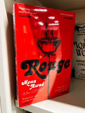 Londra, İngiltere - 12 Aralık 2025: Mona Travad tarafından Rouge için çarpıcı bir kırmızı kitap kapağı, koyu bir gül motifi ve kalın bir tipografi içerir..