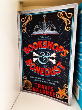 Londra, İngiltere - 12 Aralık 2025: Bir kılıç, kemikler ve canlı renklerde deniz motiflerinin yer aldığı yazı tahtası kapağı. Travis Baldree 'den Kitapçılar ve Kemikler