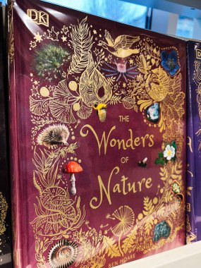 Londra, İngiltere - 12 Aralık 2025: Altın botanik motifler ve vahşi yaşam çizimleri içeren dekoratif kestane doğa kitabı kapağı, doğa severler ve klasik kütüphane dekoratörü için mükemmel.