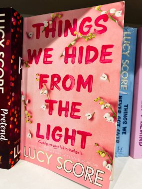 Londra, İngiltere - 12 Aralık 2025: Lucy Score 'un aşk romanı çiçeklerle kaplı pembe bir kapakta, bir kitapçıda sergilendi. Işıktan Sakladığımız Şeyler