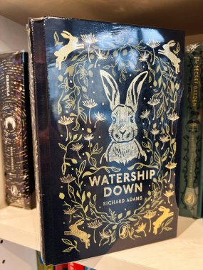 Londra, İngiltere - 12 Aralık 2025: Altın tavşanlar ve karahindiba çelenkli klasik mavi kapak, macera ve doğayı kutluyor. Watership Down by Richard Adams