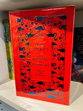 Londra, İngiltere - 12 Aralık 2025: Mavi flamingo desenli parlak kırmızı kitap kapağı ve Lewis Carroll klasiğinden cesur tipografi. Alice 'in Harikalar Diyarındaki Maceraları