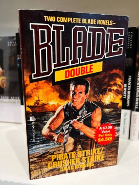 Londra, İngiltere - 12 Aralık 2025: Ateşli savaş sahnelerinin ortasında sert bir kahramanın yer aldığı klasik aksiyon kapağı. Blade Double by David Robbins