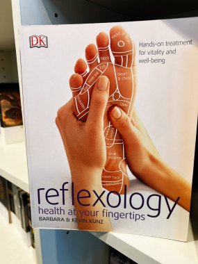 Londra, İngiltere - 12 Aralık 2025: Parlak refleksoloji kitabı kapağı bir ayak diyagramı ve basınç noktaları uygulanan eller gösteriyor.