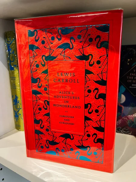 Londra, İngiltere - 12 Aralık 2025: Mavi flamingo desenli parlak kırmızı kitap kapağı ve Lewis Carroll klasiğinden cesur tipografi. Alice 'in Harikalar Diyarındaki Maceraları