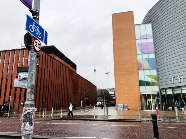 Manchester, İngiltere - 06 Aralık 2025: Tuğla bloklar, modern cam üniversite cephesi ve yürüyen insanlar ile Manchester 'da Islak Şehir Caddesi.