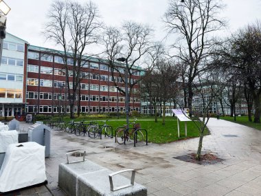 Manchester, İngiltere - 06 Aralık 2025: Manchester kampüsünde bisikletli, ağaçlı ve tuğlalı üniversite binalı bir avlu.