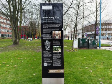 Manchester, İngiltere - Aralık 06, 2025: Manchester 'daki ağaçlı ve modern binalı otlak bir kampüste uzun bilgi işareti.