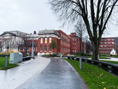 Manchester, İngiltere - Aralık 06, 2025: Manchester 'da tuğla binalar, banklar, ağaçlar ve dolambaçlı ıslak bir yol ile kapalı üniversite kampüsü.
