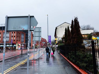Manchester, İngiltere - Aralık 06, 2025: Manchester, İngiltere 'de ıslak sokak sahnesi müşteriler, gezginler, tuğla binalar ve canlı bir şehir atmosferi.