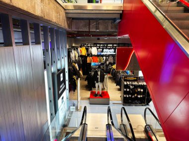 Manchester, İngiltere - 01 Aralık 2025: Raflarda ceketler, platformlarda mankenler ve yakınlarda yürüyen merdivenlerle dolu yoğun bir perakende alanı.