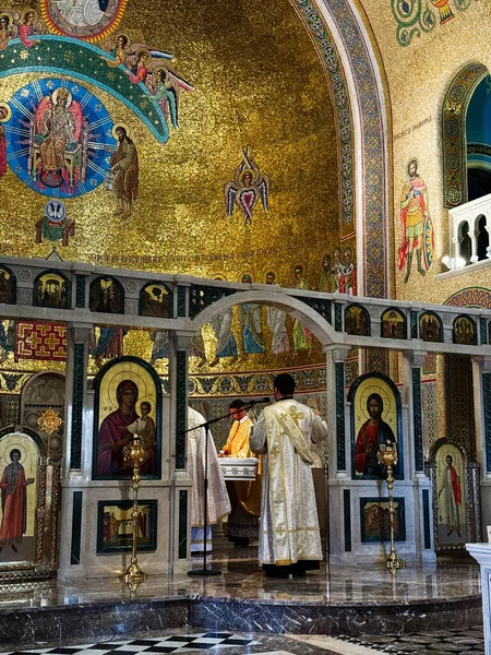 Roma, İtalya - 29 Temmuz 2025: Kutsal bir Ortodoks ayini, ikonlar ve rahiplerin tören cübbeleriyle mozaiklenmiş altın bir tapınakta gerçekleşiyor. Santa Sofia Via Boccea Caddesi.