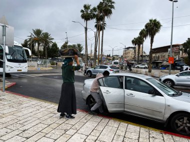 Kudüs, İsrail - 3 Aralık 2022: Kafasında yük taşıyan bir kadın ve arabaya binen bir adamla İsrail 'de sokak sahnesi. Jaffa Yolu