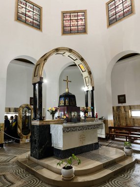Tabgha, İsrail - 3 Aralık 2022: İsrail 'de haç, kemer, mermer ve çiçek düzenlemelerinin yer aldığı huzurlu bir kilise sunağı. Güzellikler Kilisesi