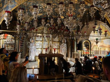 Kudüs, İsrail - 3 Aralık 2022: Ziyaret edenler, zengin dekore edilmiş bir İsrail kilisesinin kutsal sunağında mum yakarlar. Kutsal Mezar Kilisesi.