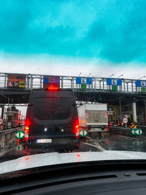 Katowice, Polonya - 29 Kasım 2025: Minibüs ve kamyon bulutlu gökyüzünün altında ıslak bir yol ve kırmızı fren lambalarıyla.