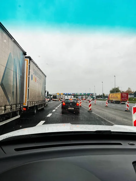 Katowice, Polonya - 29 Kasım 2025: Önünde kamyon, araba ve inşaat bariyerleri bulunan bir arabanın ön camından yağmurlu otoyol manzarası.