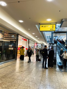 Brno, Çek Cumhuriyeti - 29 Kasım 2025: Müşteriler, içinde bir banka ve perakende mağazaları bulunan parlak bir alışveriş merkezi koridorunda yürüyorlar.