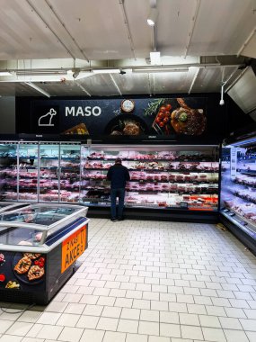 Brno, Çek Cumhuriyeti - 29 Kasım 2025: Müşteriler kalabalık bir bakkaldaki parlak soğutulmuş et tezgahından et parçaları alıyorlar.