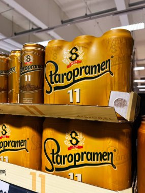 Brno, Çek Cumhuriyeti - 29 Kasım 2025: Süpermarket rafında altın Staropramen bira kutuları, kalın markalar ve parlak ambalajlar görünür.