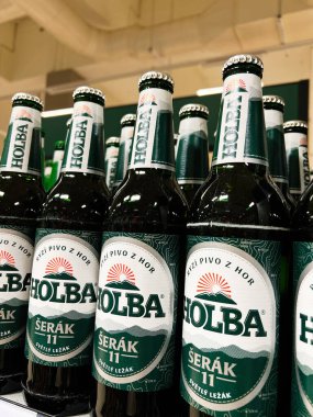 Brno, Çek Cumhuriyeti - 29 Kasım 2025: Süpermarketteki yeşil etiketli Holba bira şişelerine yakından bakmak.