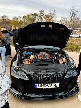 Ternopil, Ukrayna - 29 Kasım 2025: Açık hava araba fuarında motor bölümünde turuncu kaplan grafiği olan siyah bir Lexus is F.