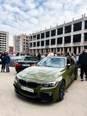 Ternopil, Ukrayna - 29 Kasım 2025: Zeytin yeşili BMW 3 Serisi F30 sedan Açık hava araba fuarında henüz tamamlanmamış bir arkaplan.