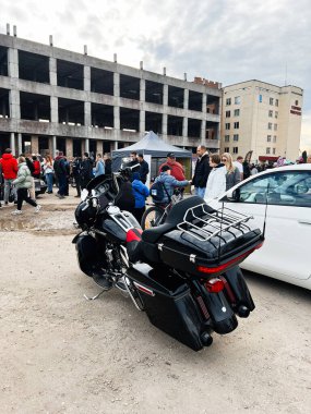 Ternopil, Ukrayna - 29 Kasım 2025: Çadırları ve bitmemiş bir bina arkaplanı olan kalabalık bir açık hava etkinliğinde toprak zeminde Harley-Davidson Caddesi Glide motosikleti turu.
