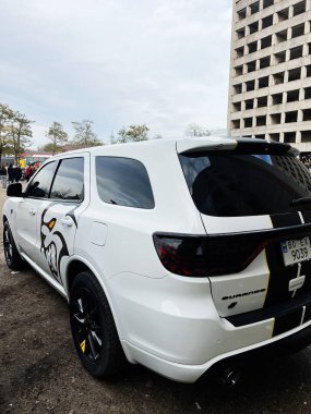 Ternopil, Ukrayna - 29 Kasım 2025: Beyaz spor aracı Dodge Durango SRT Hellcat aracı tamamlanmamış bir bina ve seyircilerin önünde park halinde..