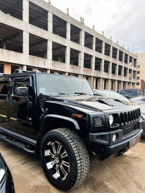 Ternopil, Ukrayna - 29 Kasım 2025: Cesur siyah bir Hummer H2 SUV kısmen inşa edilmiş beton bir yapının yanında, engebeli kentsel tarzda taşınıyor.