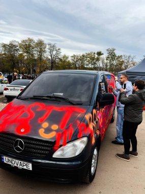 Ternopil, Ukrayna - 29 Kasım 2025: Grafiti, kalabalık ve günlük röportajların yer aldığı bir açık hava etkinliğinde gösterilen siyah minibüsü kapladı.