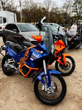 Ternopil, Ukrayna - 29 Kasım 2025: İki adet KTM 990 Macera S motosikleti, park yerinde arabalı ve seyircili, spor seyahat ekipmanları sergileniyor.