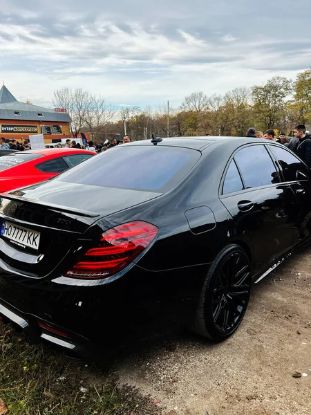 Ternopil, Ukrayna - 29 Kasım 2025: Parlak siyah Mercedes-Benz S-Sınıfı Brabus W222 sedan açık hava otomobil etkinliğinde ilginç bir kalabalığı kendine çekiyor.