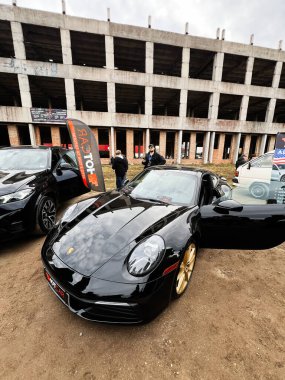 Ternopil, Ukrayna - 29 Kasım 2025: Lüks siyah Porsche 911 Carrera Bitmemiş bir endüstri binasının yakınındaki bir açık hava araba fuarında sergileniyor.