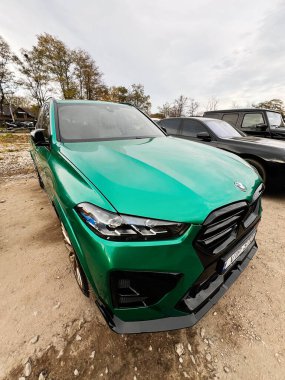 Ternopil, Ukrayna - 29 Kasım 2025: Canlı yeşil bir BMW X5 SUV çakıllı bir arazide oturuyor, kalın çizgiler ve prim modelleme sergiliyor..