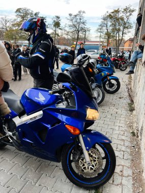 Ternopil, Ukrayna - 29 Kasım 2025: Mavi Honda VFR motosikletli motorcular, seyirciler tuğla duvarın yakınındaki bir açık hava gösterisini izlerken bir araya geldiler.