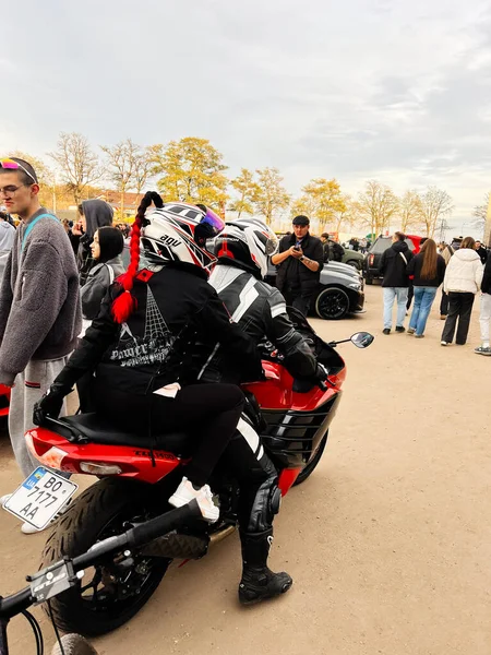 Ternopil, Ukrayna - 29 Kasım 2025: Bir açık hava etkinliğinde, kask ve teçhizat giymiş, canlı bir kalabalığın arasında kırmızı bir spor bisikleti süren iki sürücü.