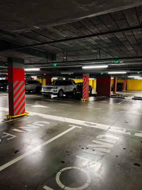 Lviv, Ukrayna - 29 Kasım 2025: Cipli loş bir garaj, kırmızı çizgili sütunlar ve kalın sarı güvenlik engelleri kentsel park ortamını oluşturur.