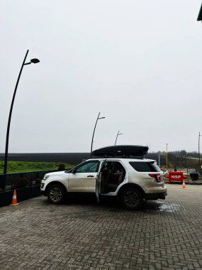 Edinet, Moldova - 29 Kasım 2025: Çatı kutulu beyaz Ford Explorer SUV ve yol kenarında bulutlu bir park alanında açık kapı.