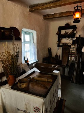 Khodakhkiv, Ukrayna - 29 Kasım 2025: Sıcak fener ışığı altında ahşap masa, kurutulmuş çiçekler ve antika kaplar ile Ukrayna mutfağı sahnesi.